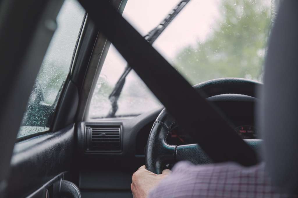 person holding vehicle steering wheel inside car