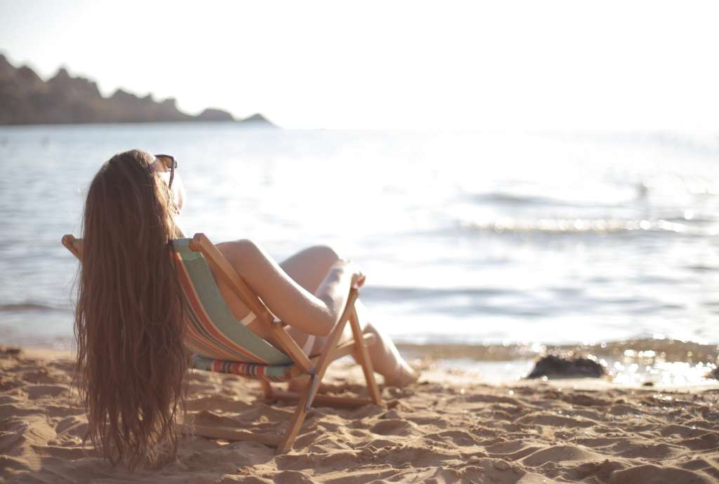 woman in white bikini reclining in beach chair