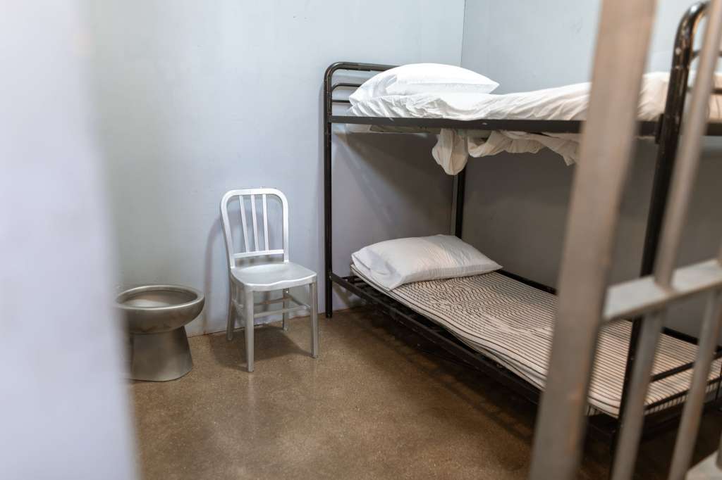 a bunk bed with striped foam mattress in a prison cell