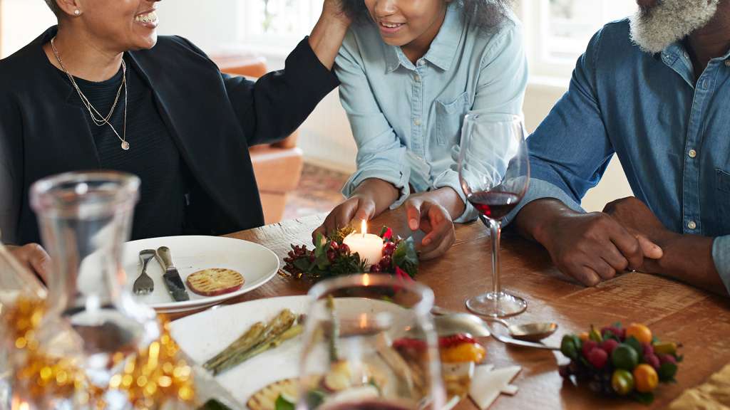 Teenage girl talking with family at dining table during Christmas festival