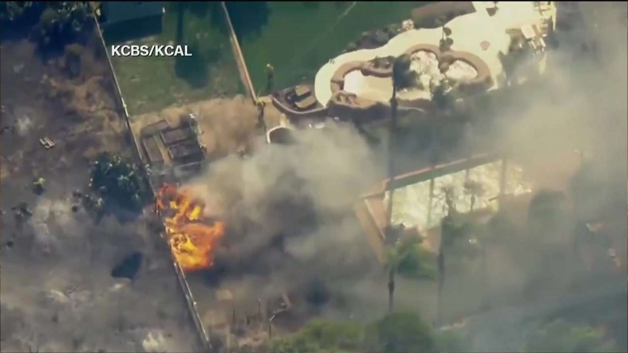 Multiple Southern California homes are ablaze in a fast-moving wildfire fueled by hot, windy weather
